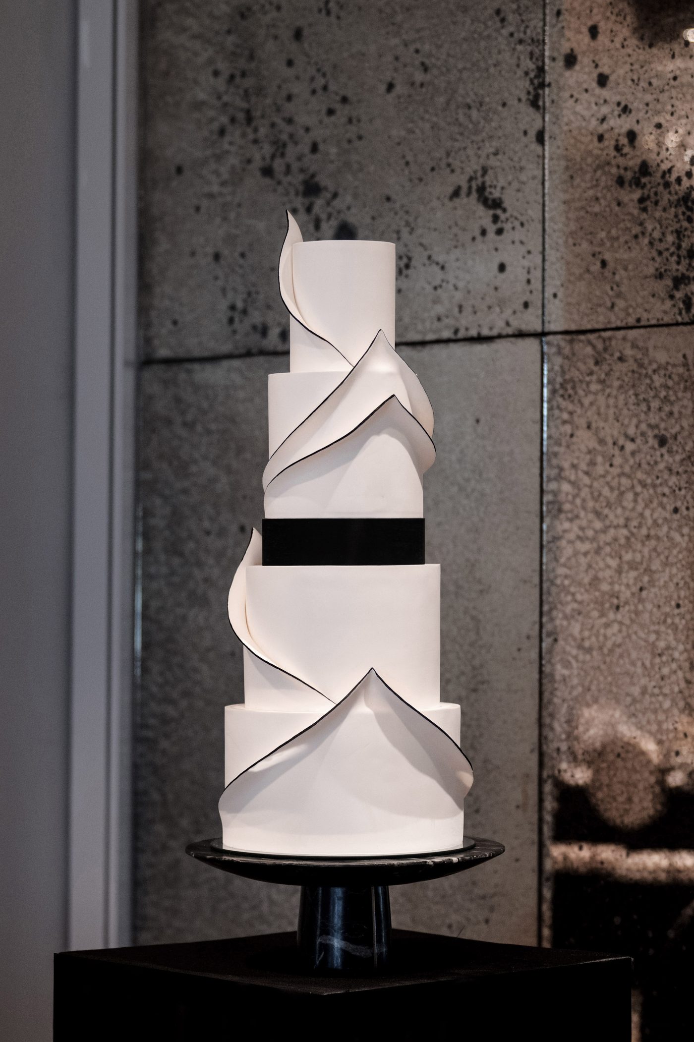 Modern white sculptural cake with black-edged sugar panels and a black band
