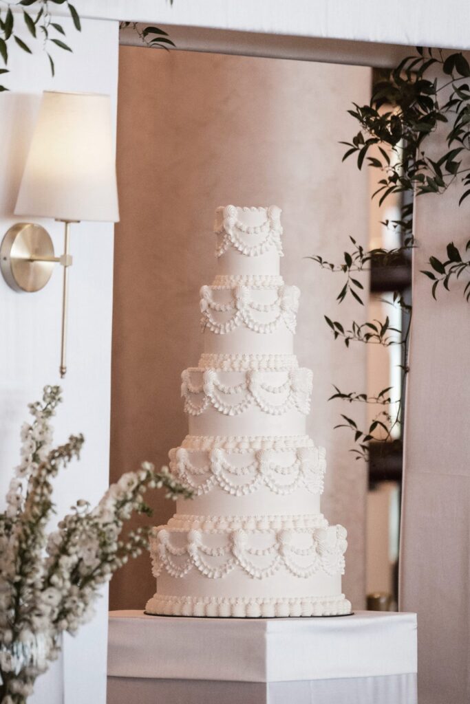 Five-tier white wedding cake with classic piped swags and shell borders