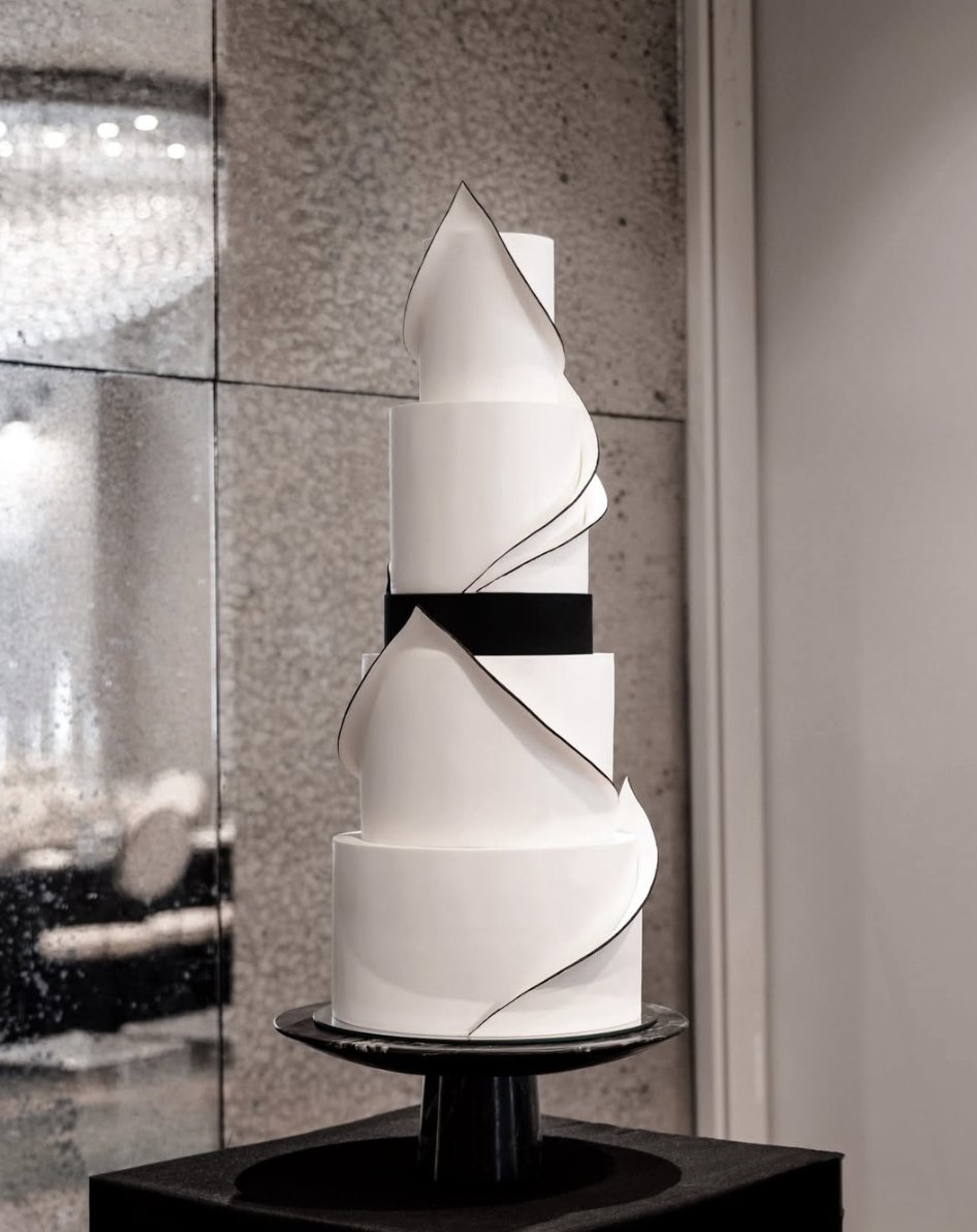 Modern sculptural white cake with black-edged sugar panels and a black ribbon
